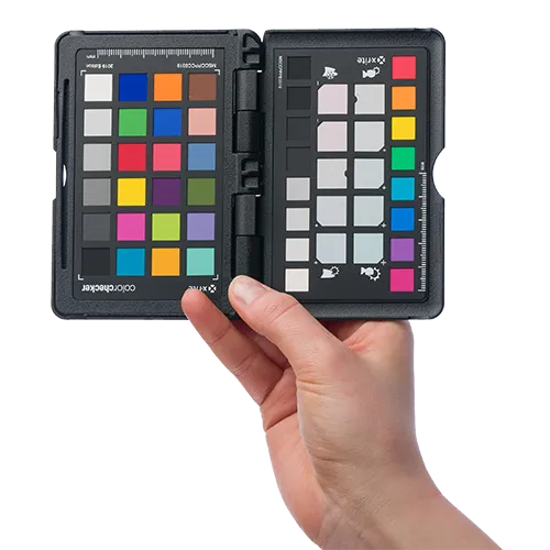 Ręka trzyma kontroler kolorów, narzędzie używane do zapewnienia dokładnego odwzorowania kolorów w fotografii i mediach cyfrowych.