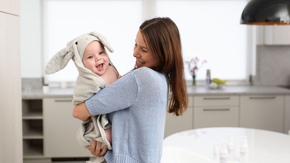 Kobieta trzymająca dziecko w kuchni. Dziecko ma na sobie kostium króliczka.