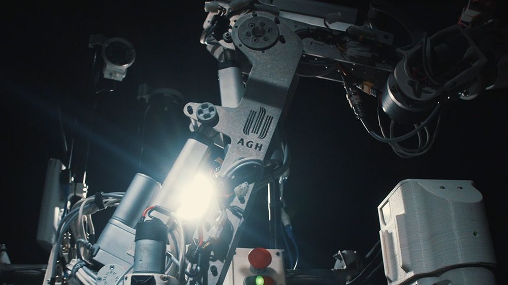 Ramię robota z jasnym światłem świecącym z jego środka, ustawione na ciemnym tle.